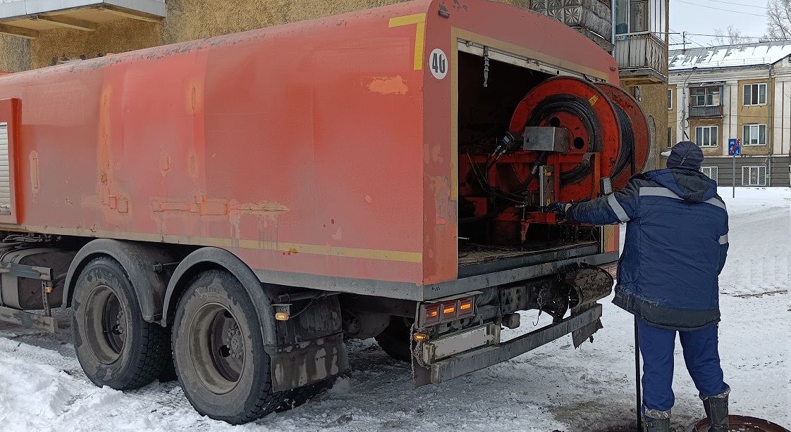 Каналопромывочная машина и работник прочищают засор в канализационной системе в Приютном